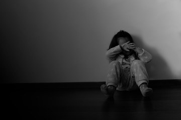 sad little girl sitting on the floor in black and white background