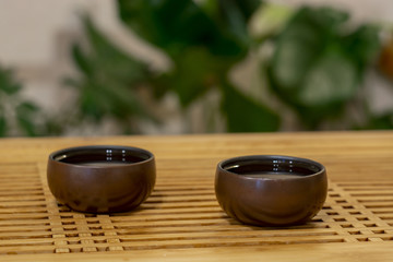 Two cups of tea on a Chinese table on a green background.