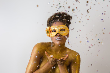 Young woman costumes for the carnival blowing confetti for the camera