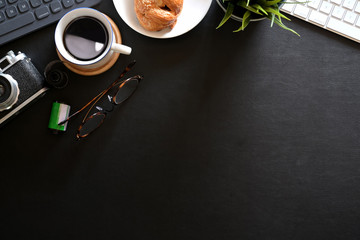 Office leather dark desk table with croissant, coffee, vintage camera, film and copy space