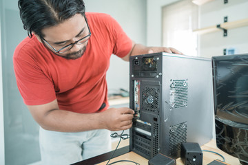 portrait of technician install a new hardware a part of personal computer in office room