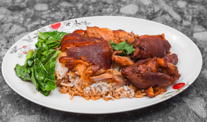 German pork knuckle with rice, vegetable and fruit served with sauce on wooden table.