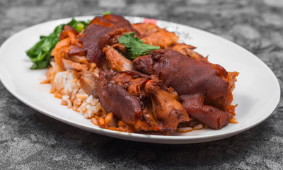 German pork knuckle with rice, vegetable and fruit served with sauce on wooden table.