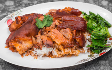 German pork knuckle with rice, vegetable and fruit served with sauce on wooden table.