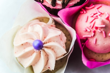 Three Cupcakes In Pink Wrappers Against A White Background