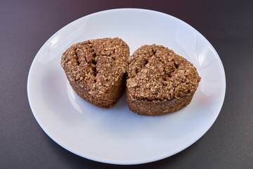 Vegan bread made at home with wheat germ and buckwheat is lying on a white plate on a black background. healthy food. natural products