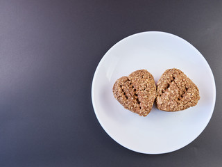 dietary homemade bread heart shape two rolls on a white plate and a dark background. healthy food on the table. fresh bread. copy space. top view