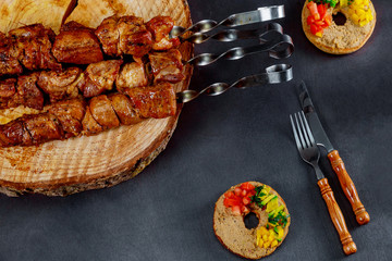 Shish kebab of pork on the black wooden table.