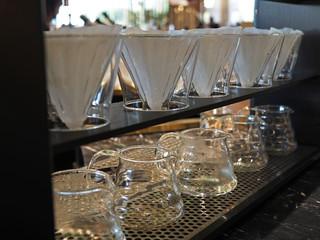 Closeup of clear jars with hot steam and coffee paper filter on a shelve. Selected focus.