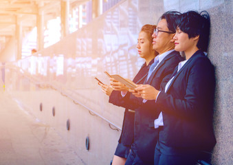Business team. They are talking about Business  and play smart phone. They are standing on walkway.Photo concept Business team.