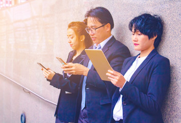 Business team. They are talking about Business  and play smart phone. They are standing on walkway.Photo concept Business team.