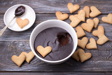 Bowl of delicious chocolate mousse and heart cookies for Valentine's Day on wooden background