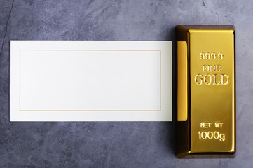 An ingot of gold metal bullion of pure brilliant on a gray textured background.