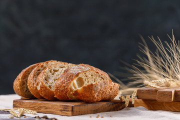 Sliced homemade bread on a board close-up on a dark background. The concept of healthy food and traditional bakery.