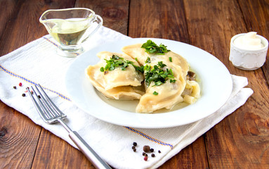 Dumplings, filled with mashed potato in plate on wooden table. Varenyky, vareniki, pierogi, pyrohy