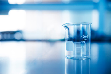 single glass beaker in chemical science laboratory for research and education in blue background