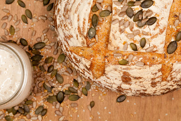 close up of sourdough loaf and starter with pumpkin seeds