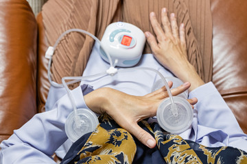 Young modern mother uses automatically electric breast pump feeding for her baby. Top view.