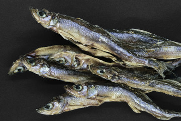 Bunch of dry small European smelt fishes on black background