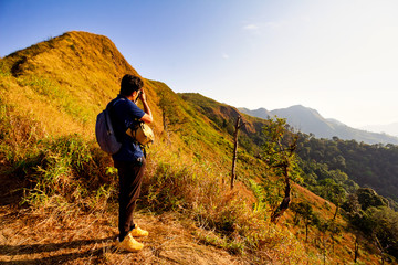 Fototapeta premium Young hiker taking a photography along path of terkking. Photographer taking photo at mountain peak.