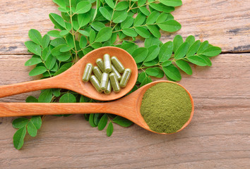 moringa leaf and powder capsule on  a wooden background