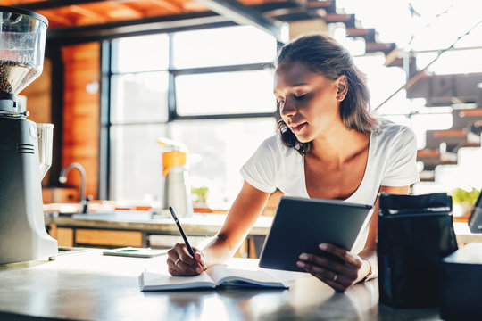 Woman Standing By A Counter While Reviewing Business Files