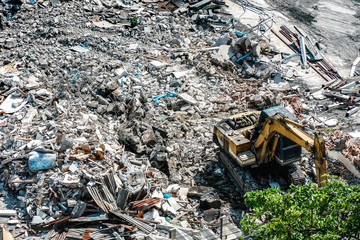Construction working. The destroyed building is dismantled by a yellow excavator. Dismantling of...