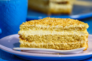 A slice of sponge cake with walnuts, next to a cup of coffee.