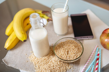 Rice milk in a glass Cup and fruit with scattered grains of rice on table in the kitchen. Diet...