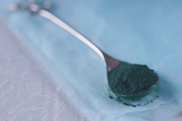 Spirulina powder on a spoon close-up.