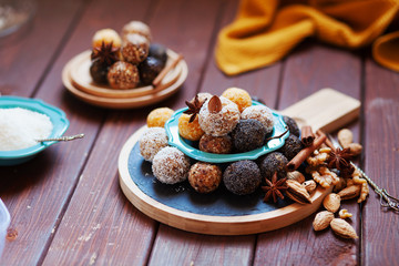 Fototapeta na wymiar Vegan organic energy bites with nuts, chia, dates, coconut and dried fruits, healthy raw dessert snacks on wooden table