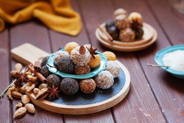 Vegan organic energy bites with nuts, chia, dates, coconut and dried fruits, healthy raw dessert snacks on wooden table