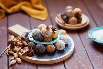 Vegan organic energy bites with nuts, chia, dates, coconut and dried fruits, healthy raw dessert snacks on wooden table