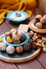 Fototapeta na wymiar Vegan organic energy bites with nuts, chia, dates, coconut and dried fruits, healthy raw dessert snacks on wooden table