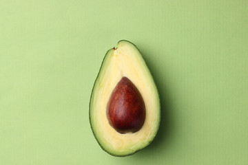 half avocado with seed on a green background top view