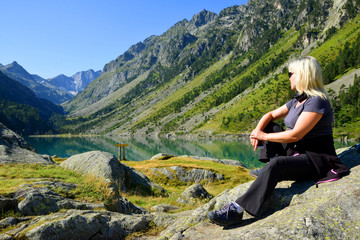 Fototapeta premium Tourist sitting on rock at Gaube lake. Hautes Pyrenees, France.