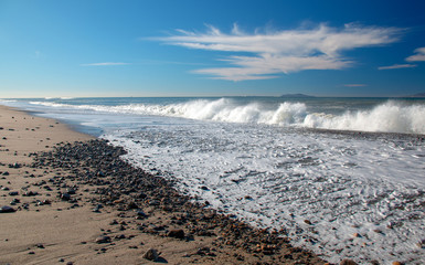 Wave foam washing over gravel on beach at McGrath State Park in Oxnard California United States
