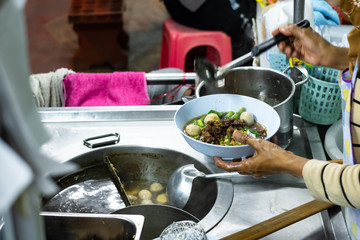 Cooker making thai noodle of jumbo beef ball with meaty sell on cart at night. Thai street food. Thai local food.