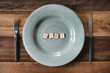 a word DIET made from a alphabet tiles in a empty plate. concept of dieting, lose weight and healthy eating