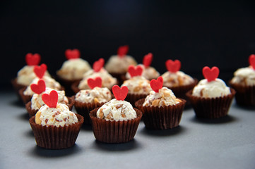 Tasty cupcakes on gray background with hearts. Lots of vegan cupcakes