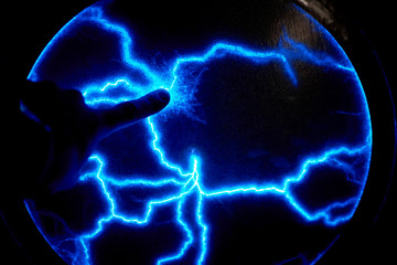 Finger touch electric plasma ball on a dark background. Static electricity model