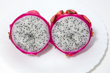 dragon fruit cut in half lying on a white plate