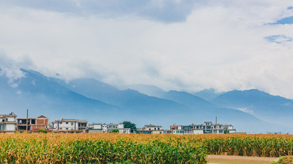 Houses and fields under Cangshan Mountains covered in clouds, in Dali, Yunnan, China