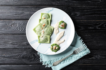 Plate with tasty ravioli on wooden table