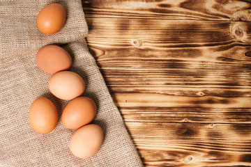 Chicken eggs on a napkin of burlap on wooden table.  Top view
