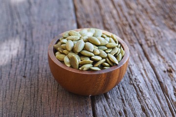 Pumpkin grain in wooden bowl on classic wooden table background, cereal