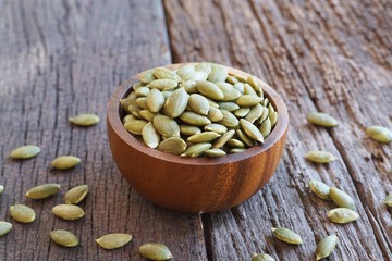 Pumpkin grain in wooden bowl on classic wooden table background, cereal