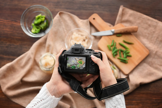 Young woman taking picture of vegetables on table