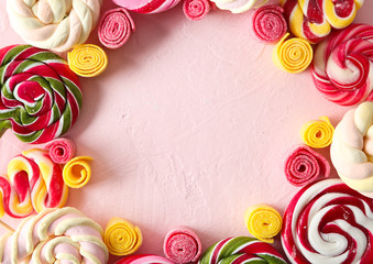 Frame made of different sweets on color background