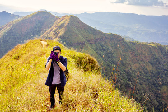 Young hiker taking a photography along path of terkking. Photographer taking photo at mountain peak.